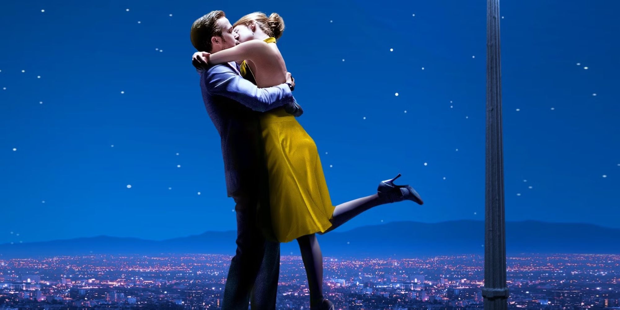 Ryan Gosling and Emma Stone kiss in front of the L.A. cityscape at night in the La La Land poster.