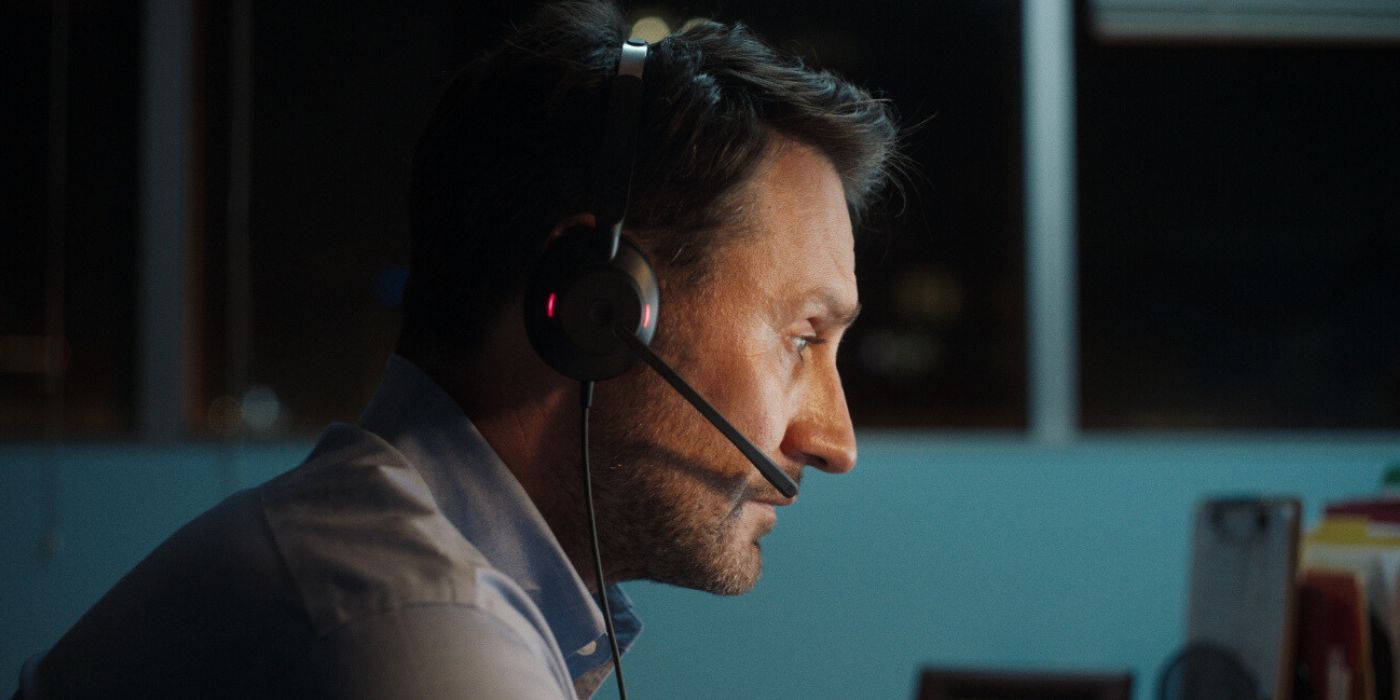 Josh Stewart as Steven looking intently at a computer wearing headset in Lifeline.