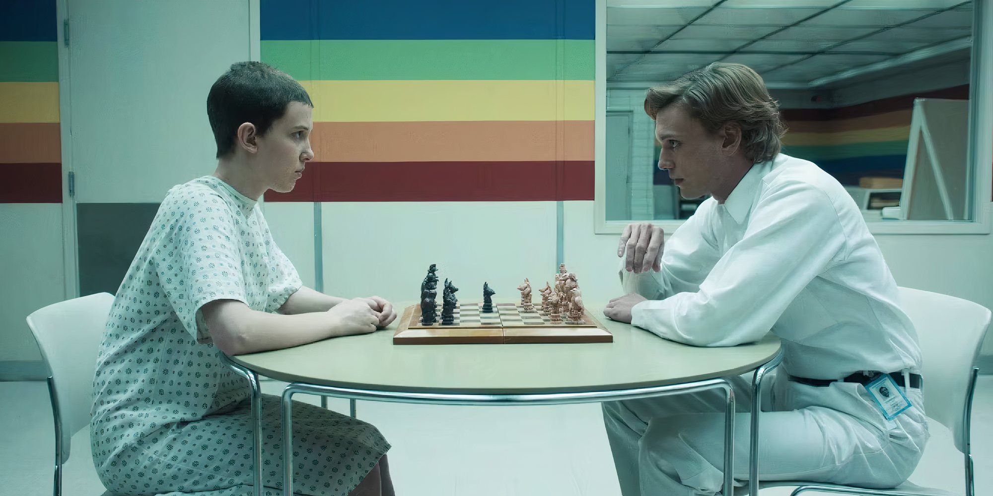 Millie Bobby Brown as Eleven and Jamie Campbell Bower as Henry in Stranger Things looking at each other while playing chess