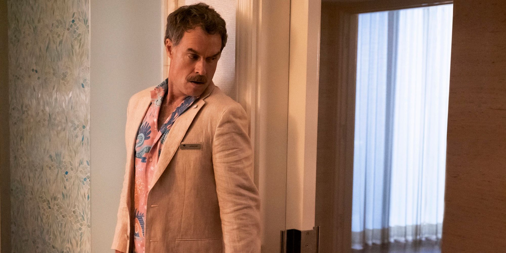 Murray Bartlett as Armond hiding around a corner in The White Lotus Season 1.