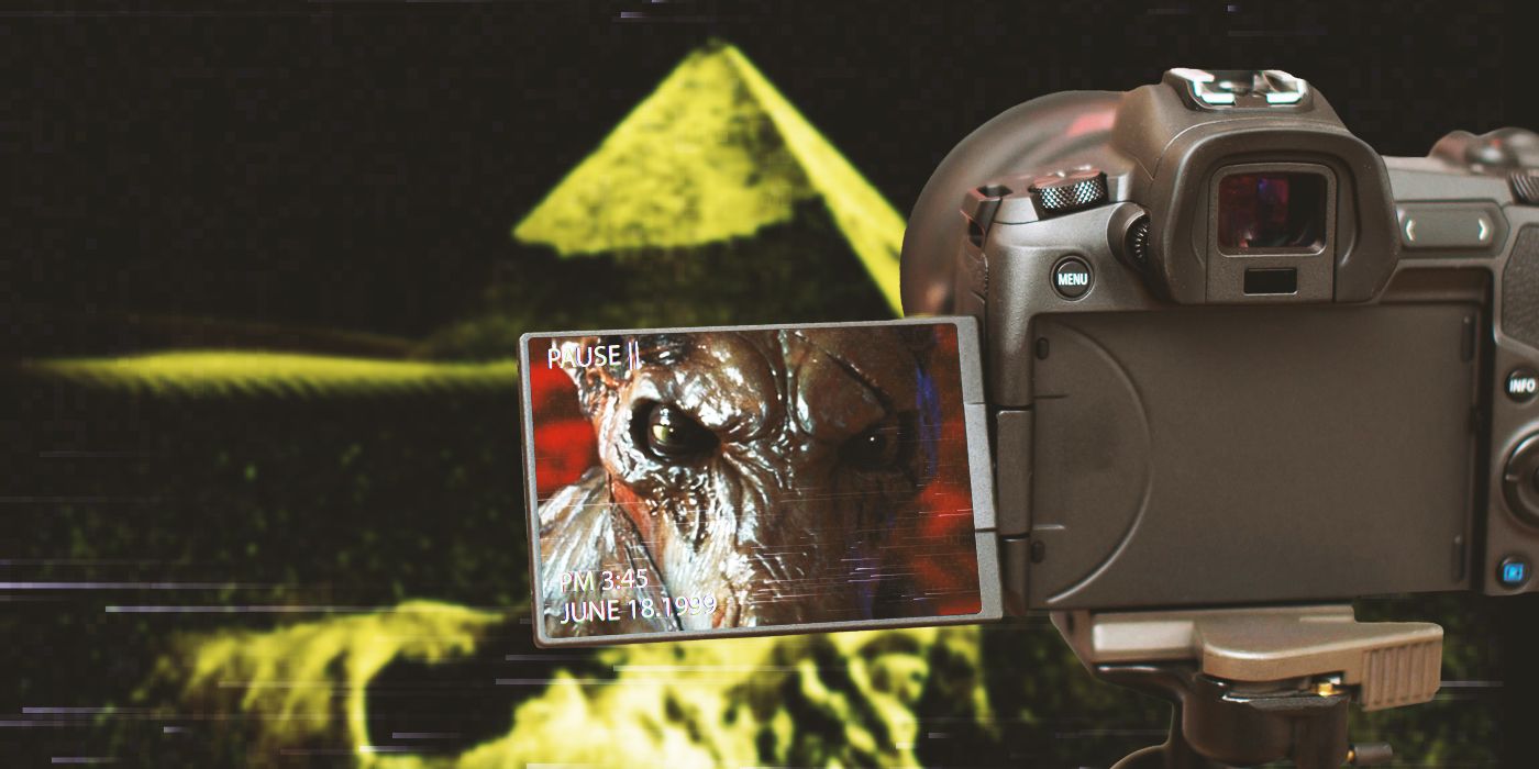 A video camera in front of the vague silhouette of a pyramid, with an animal-like creature shown on the camera screen.