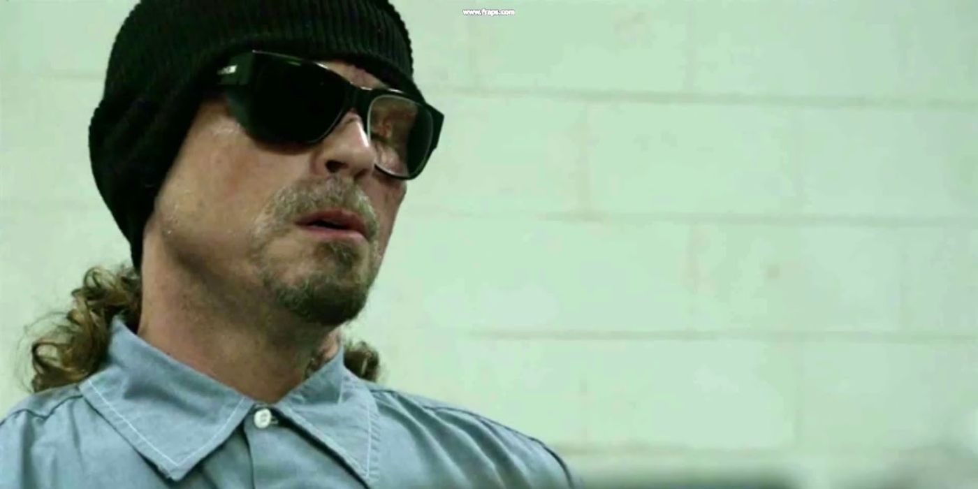 Kurt Sutter wearing glasses and a hat and looking down at something in Sons of Anarchy.