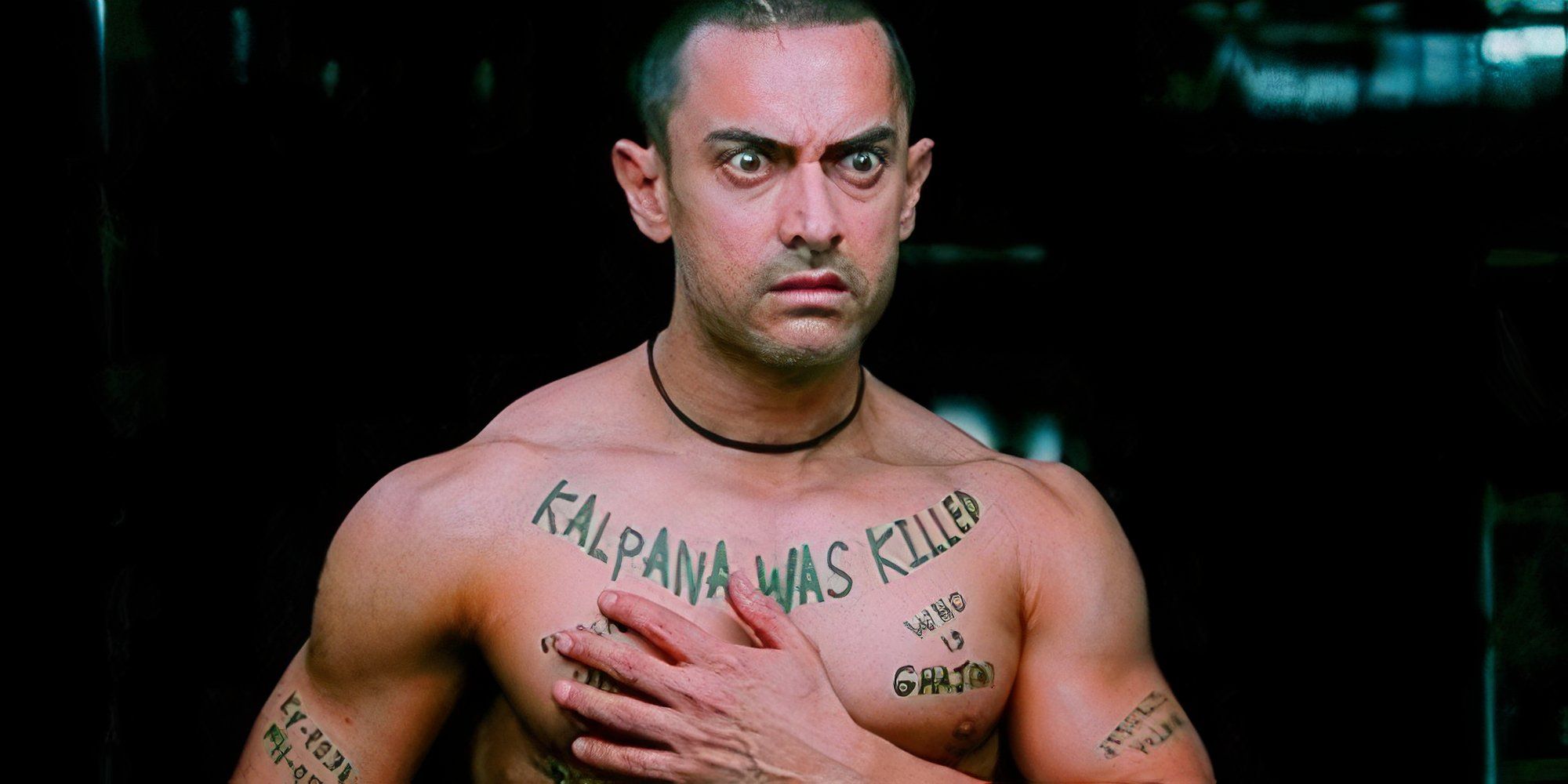 aamir. khan is reading the tattoos on his chest in ghajini.
