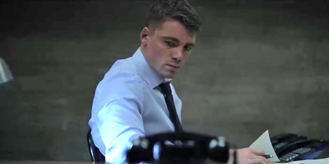 Peter in a basement looking at a phone in a scene from The Night Agent.