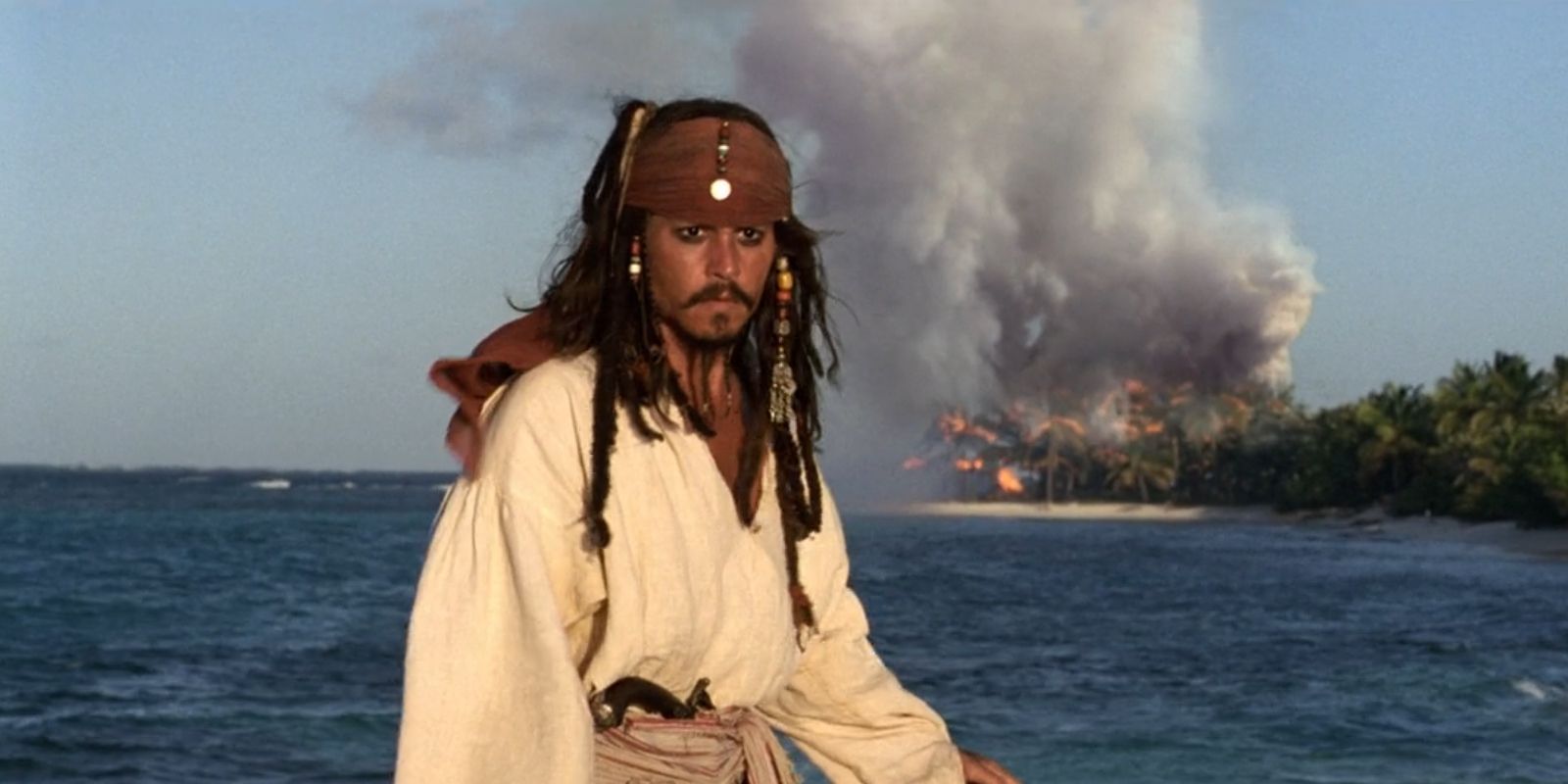 Jack Sparrow stands in front of burning trees in 'Pirates of the Caribbean: The Curse of the Black Pearl'.