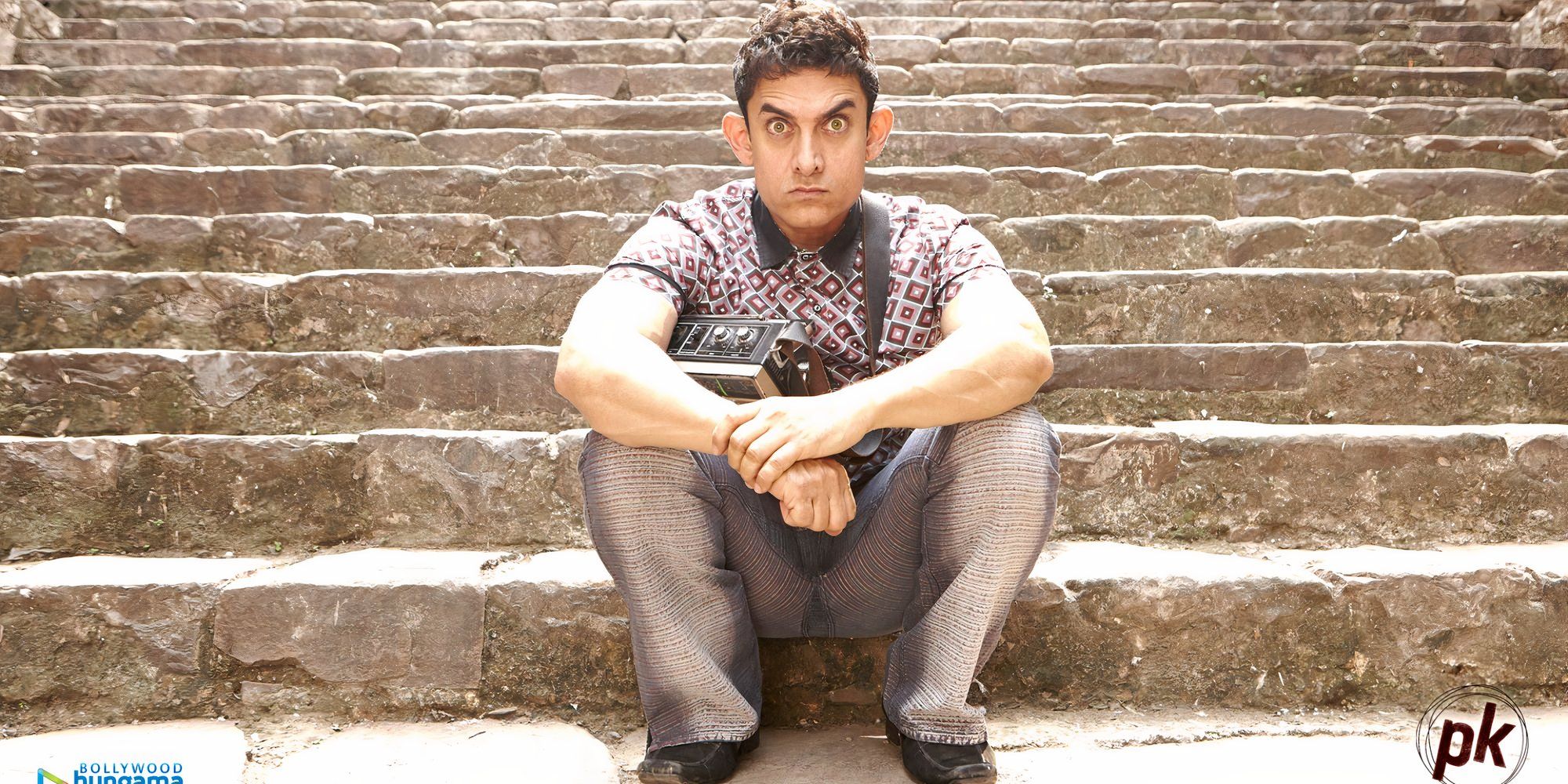 aamir khan is sitting on stairs and looking in the distance in pk.