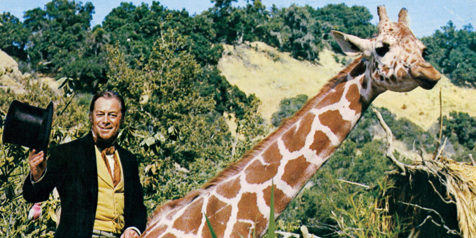 Rex Harrison, waving his top hat, riding a giraffe in a prairie in 'Doctor Dolittle'