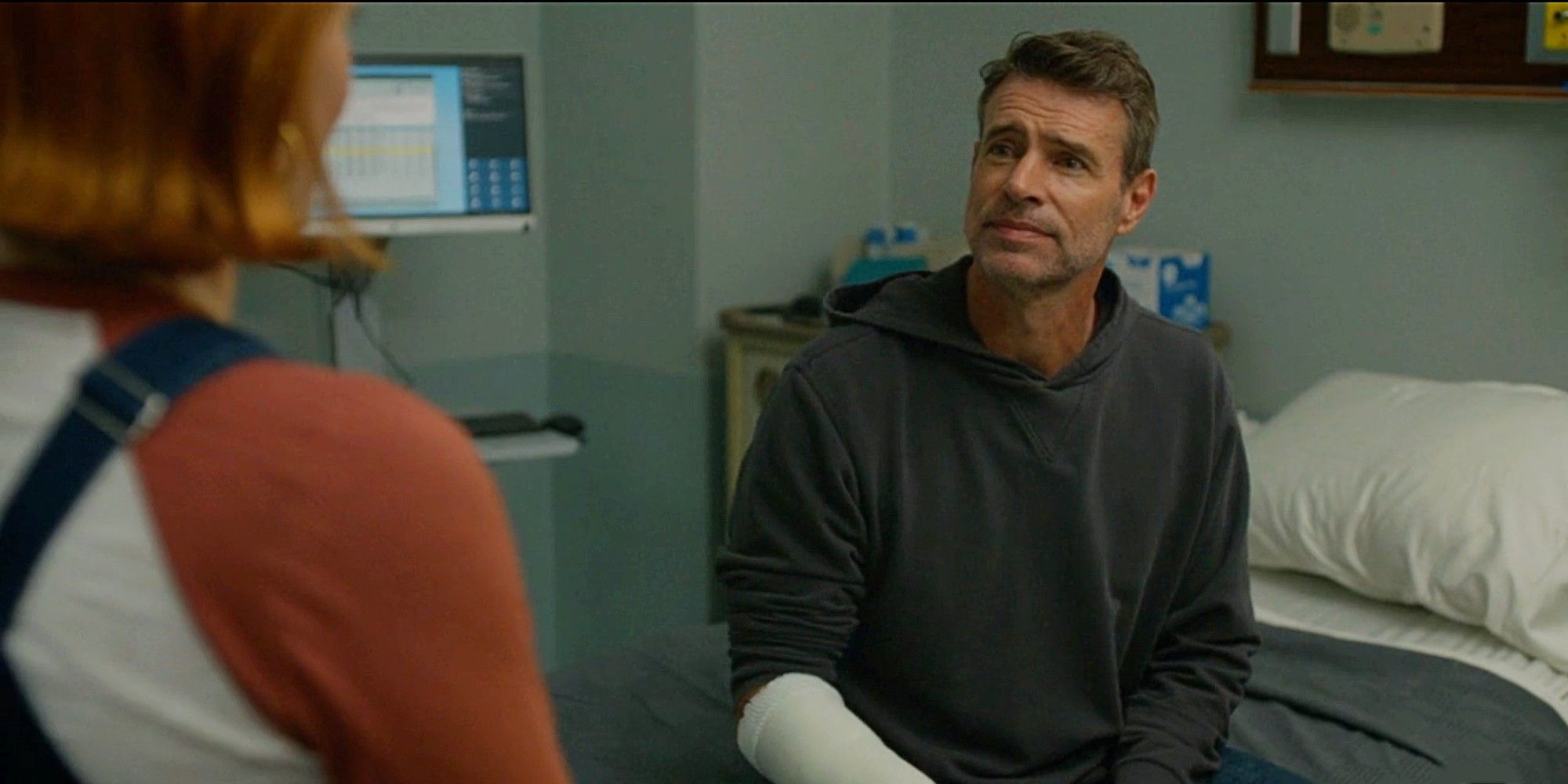 Scott Foley as Dr. Seth McDale, sitting on a hospital bed and looking at Angie Polaski in Will Trent