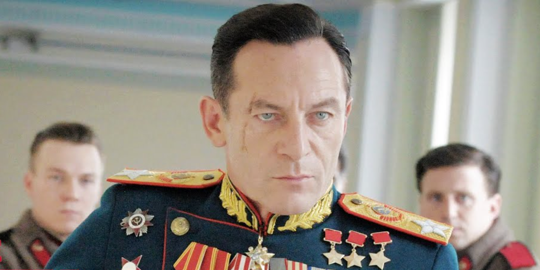 Jason Isaacs in a military uniform with a scar on his face sits in a room with others in The Death of Stalin.
