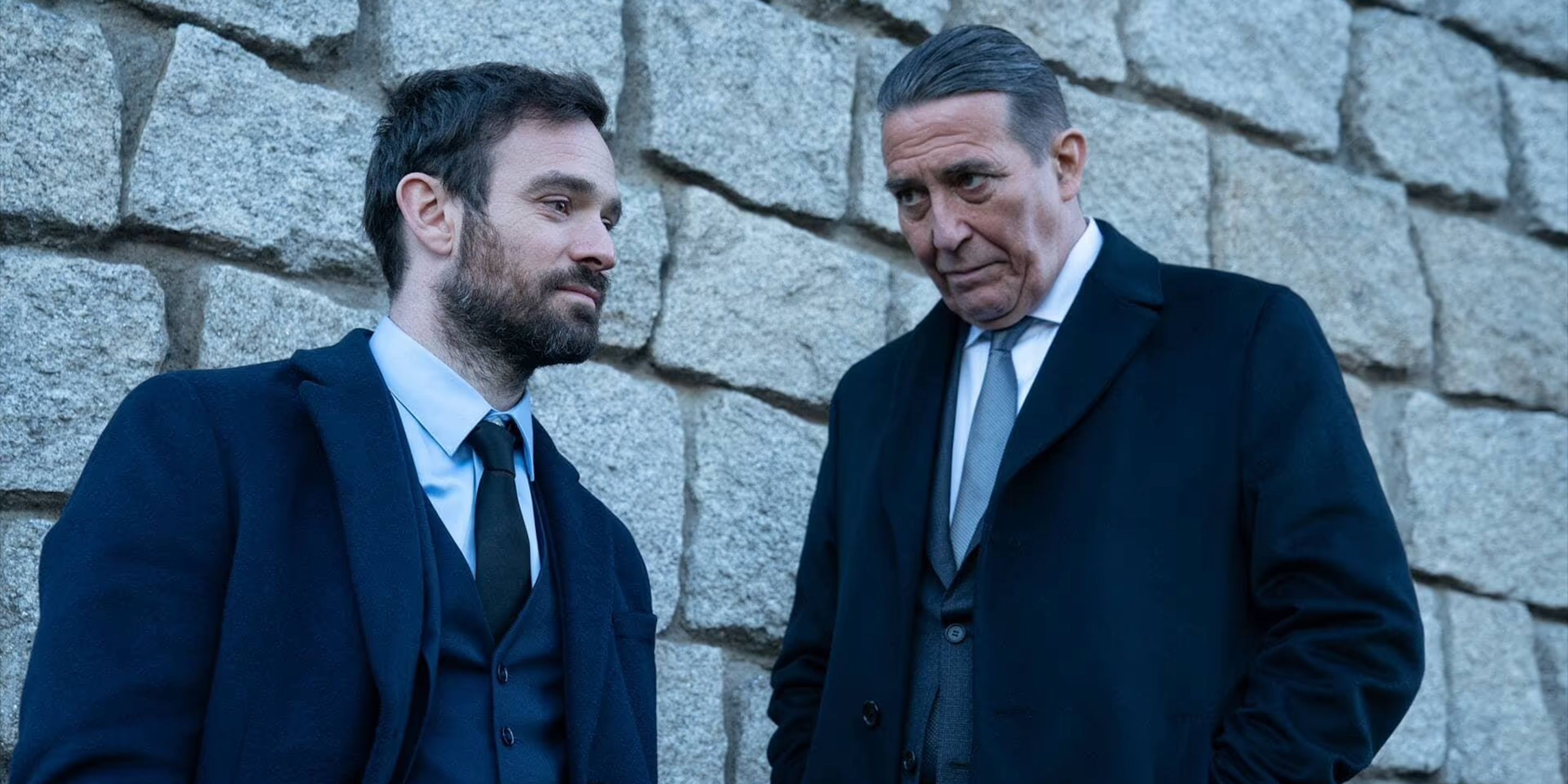 Ciarán Hinds and Charlie Cox as Eamon and Michael, talking next to a brick wall in Kin