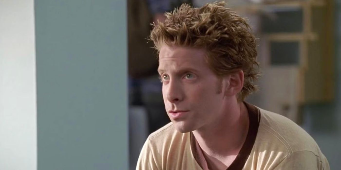 Seth Green's Oz from Buffy the Vampire Slayer wears a cream-colored shirt with a brown collar and talks to someone off screen