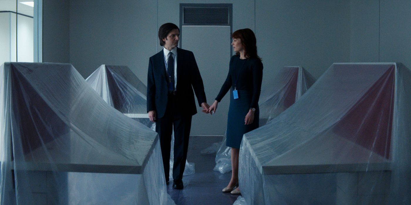 Adam Scott and Britt Lower holding hands in an empty office covered in sheets