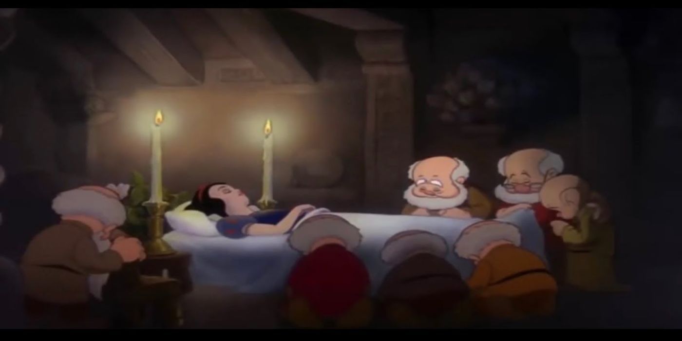 The seven dwarfs bow their heads around Snow White&rsquo;s body