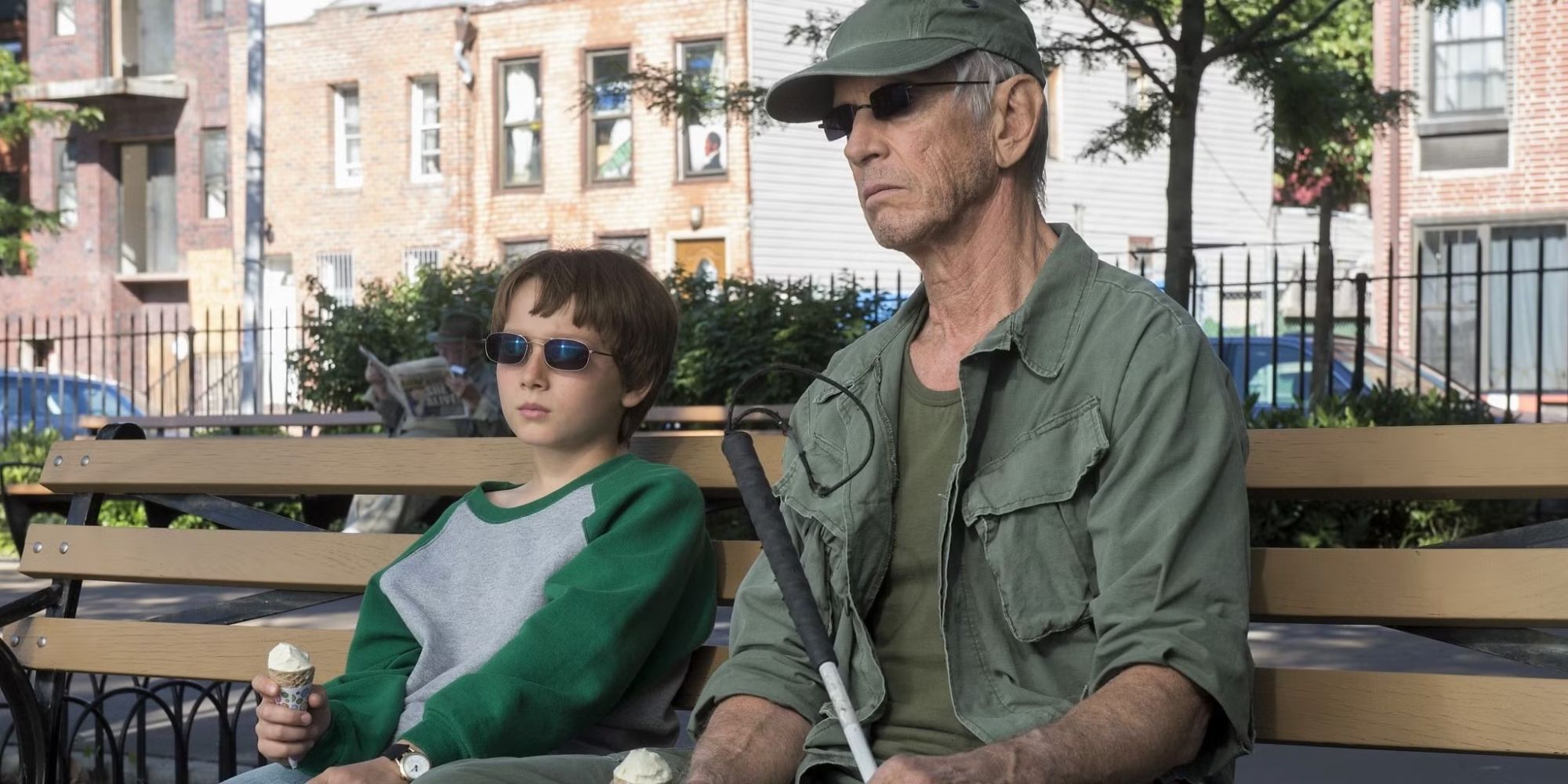 Stick and a young Matt Murdock sit on a bench together, both wearing sunglasses in Daredevil.