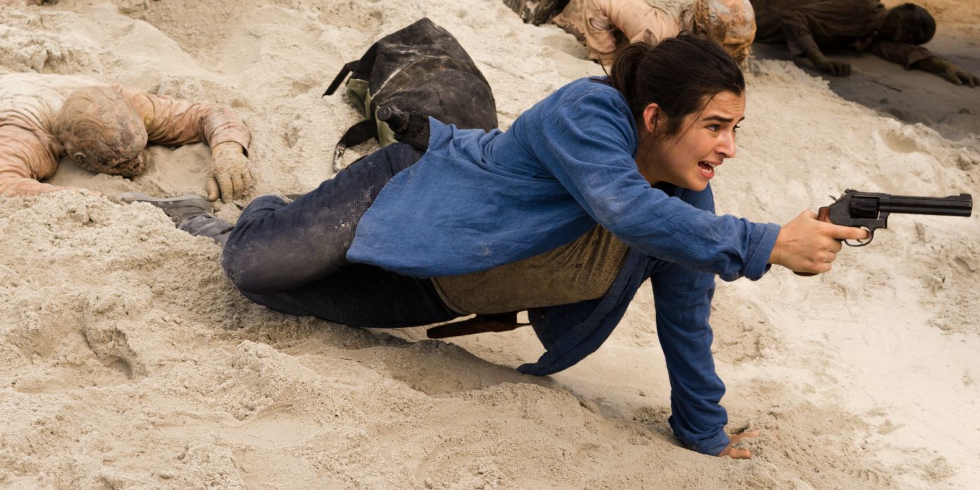 Alanna Masterson as Tara lying on the sand and pointing a gun at something in The Walking Dead episode Swear.