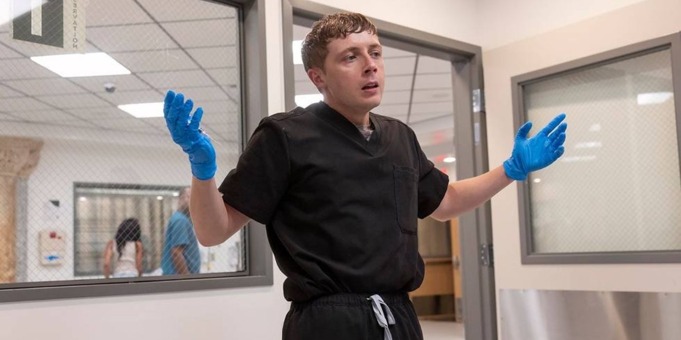 Gerran Howell wearing messy scrubs and holding up gloved hands in The Pitt Episode 4