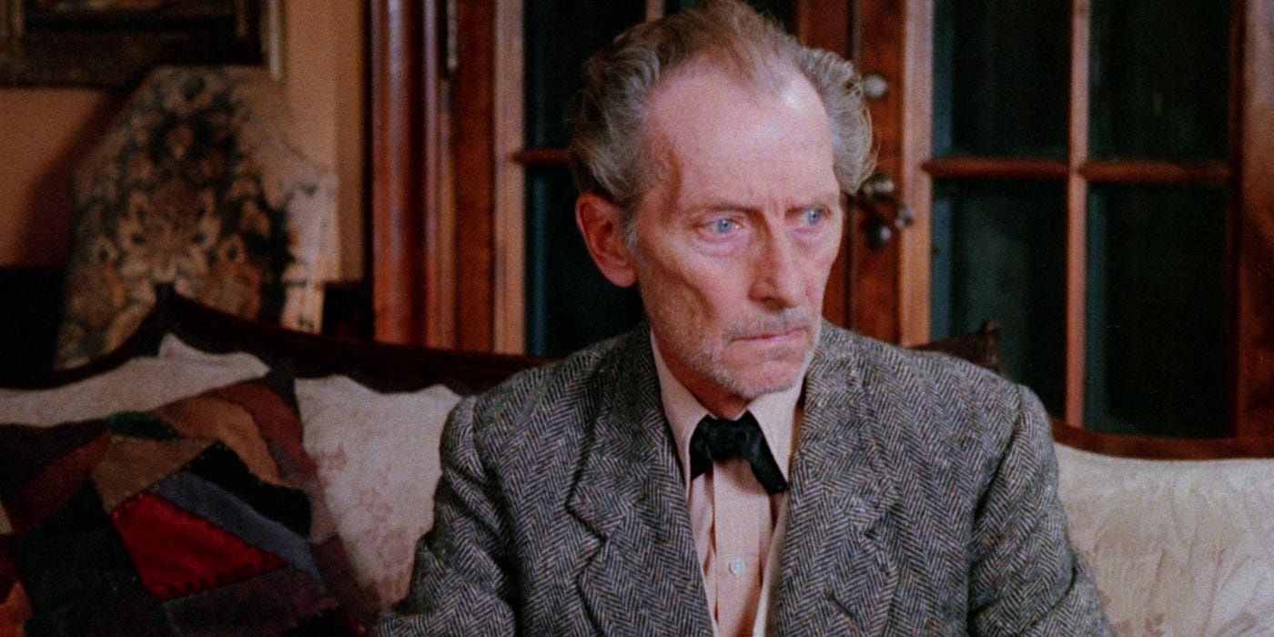 Peter Cushing, as Wilbur Gray, sitting on a sofa and looking agitated at a cat in &lsquo;The Uncanny.'