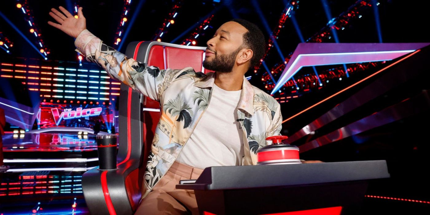 John Legend poses in his chair with 'The Voice' logo.