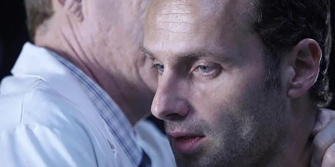 A close-up of Rick looking shocked as Dr. Jenner whispers in his ear on The Walking Dead.