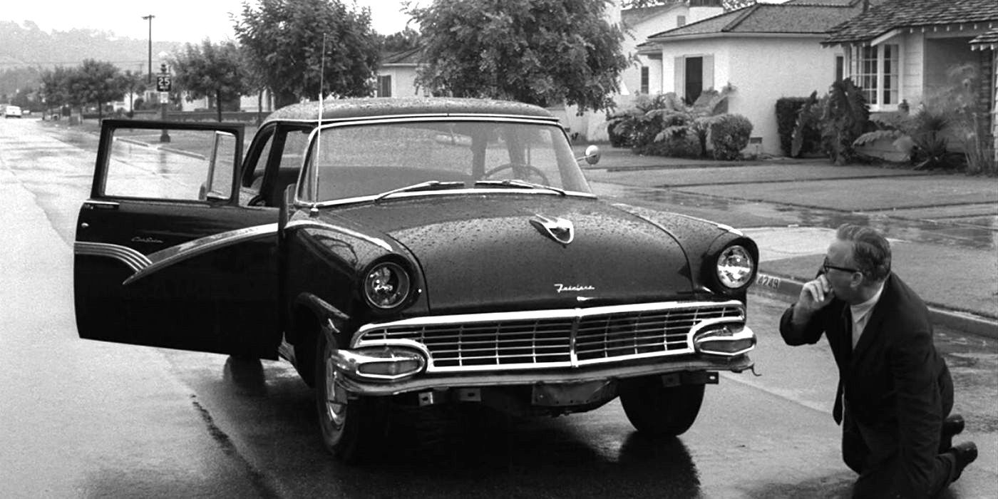 Oliver on his hands and knees in front of a car looking distraught in The Twilight Zone episode You Drive.