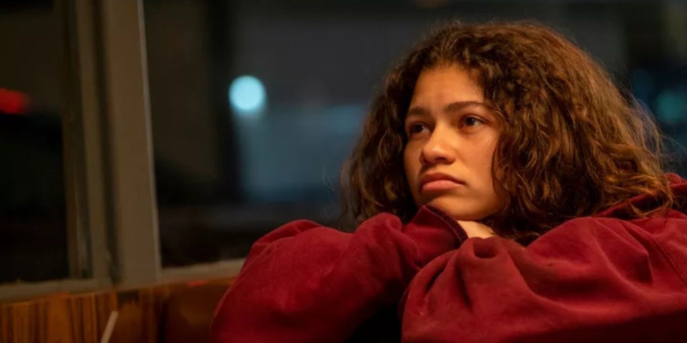 Zendaya as Rue looking sullen with arms folded and head resting on them in 'Euphoria'.