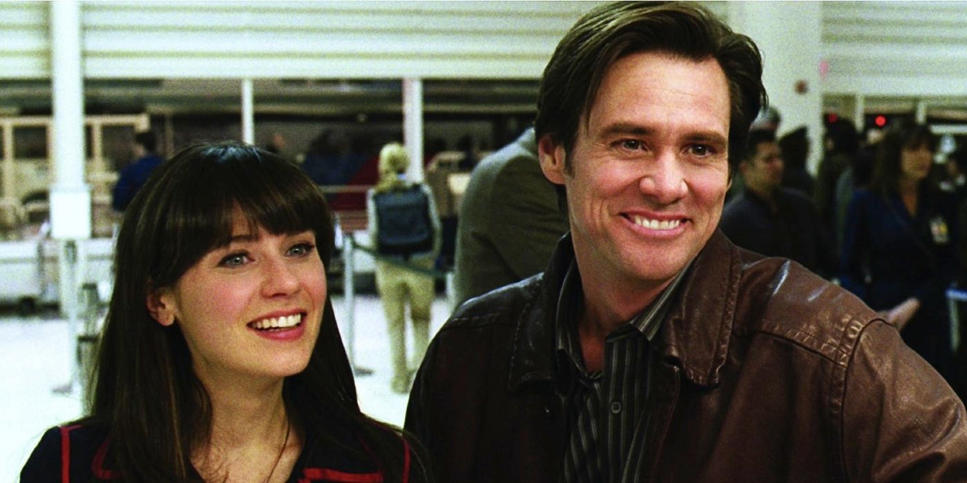 Zooey Deschanel and Jim Carrey stand at the counter in an airport and smile in Yes Man.