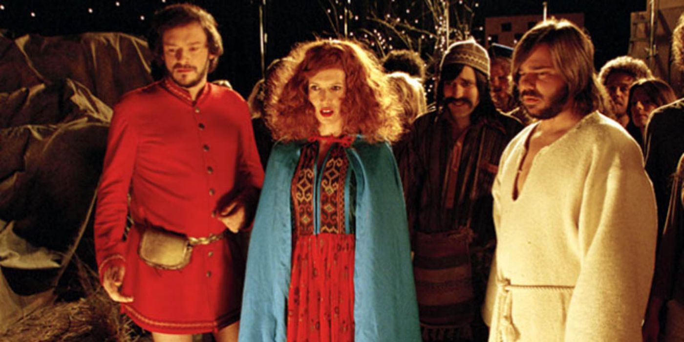 Julian Barratt, Julia Davis and Matt Berry in AD/BC: A Rock Opera stand in a crowd and look off-screen.