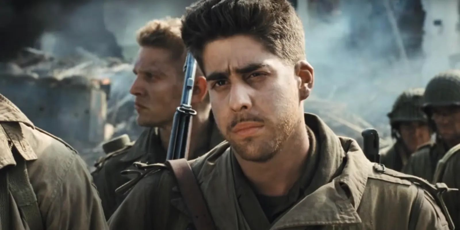 Adam Goldberg in military clothing in a crowd of soldiers with a weapon on his back in Saving Private Ryan.