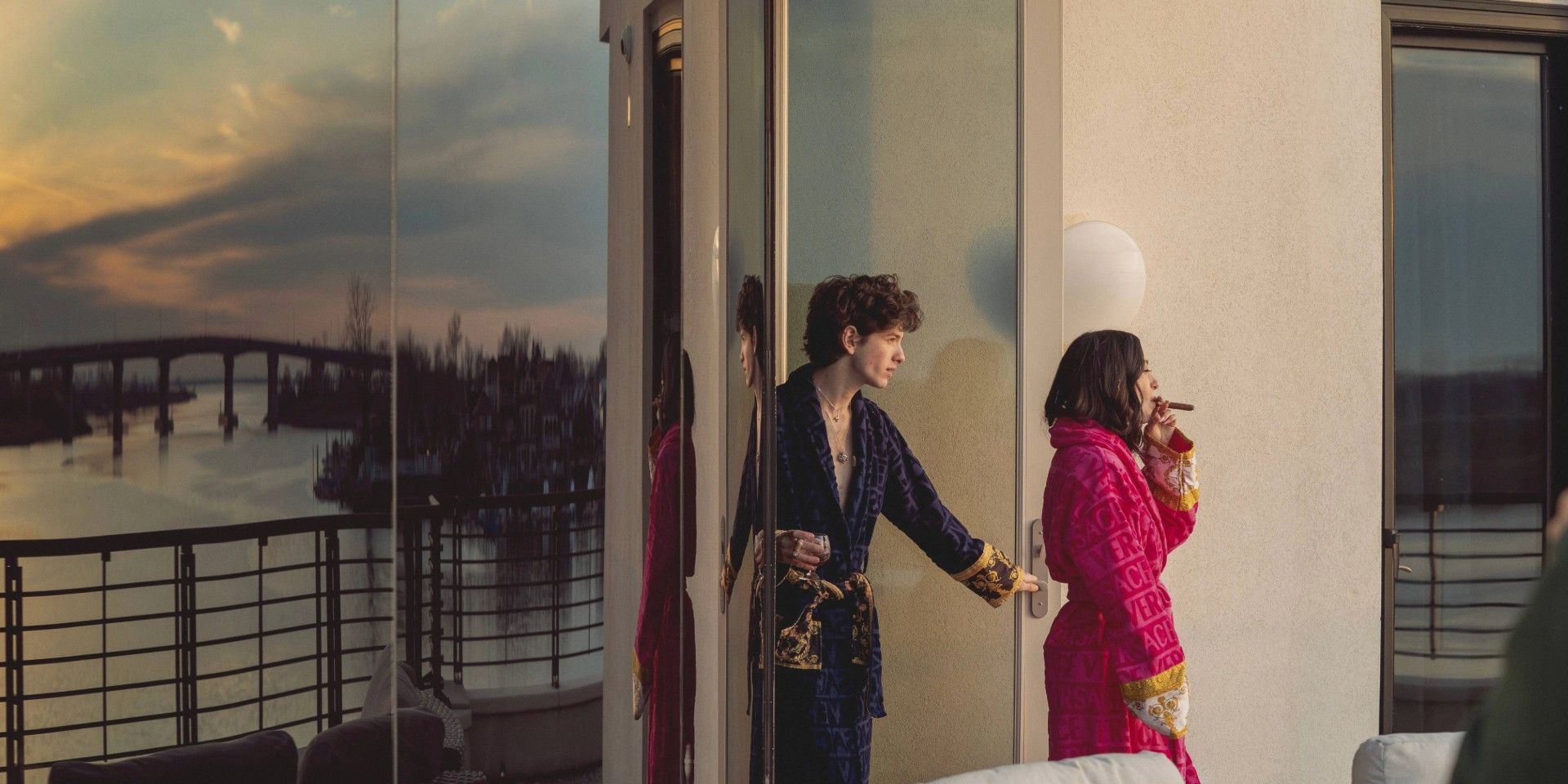 Anora and Vanya in bath robers walking into a balcony in Anora