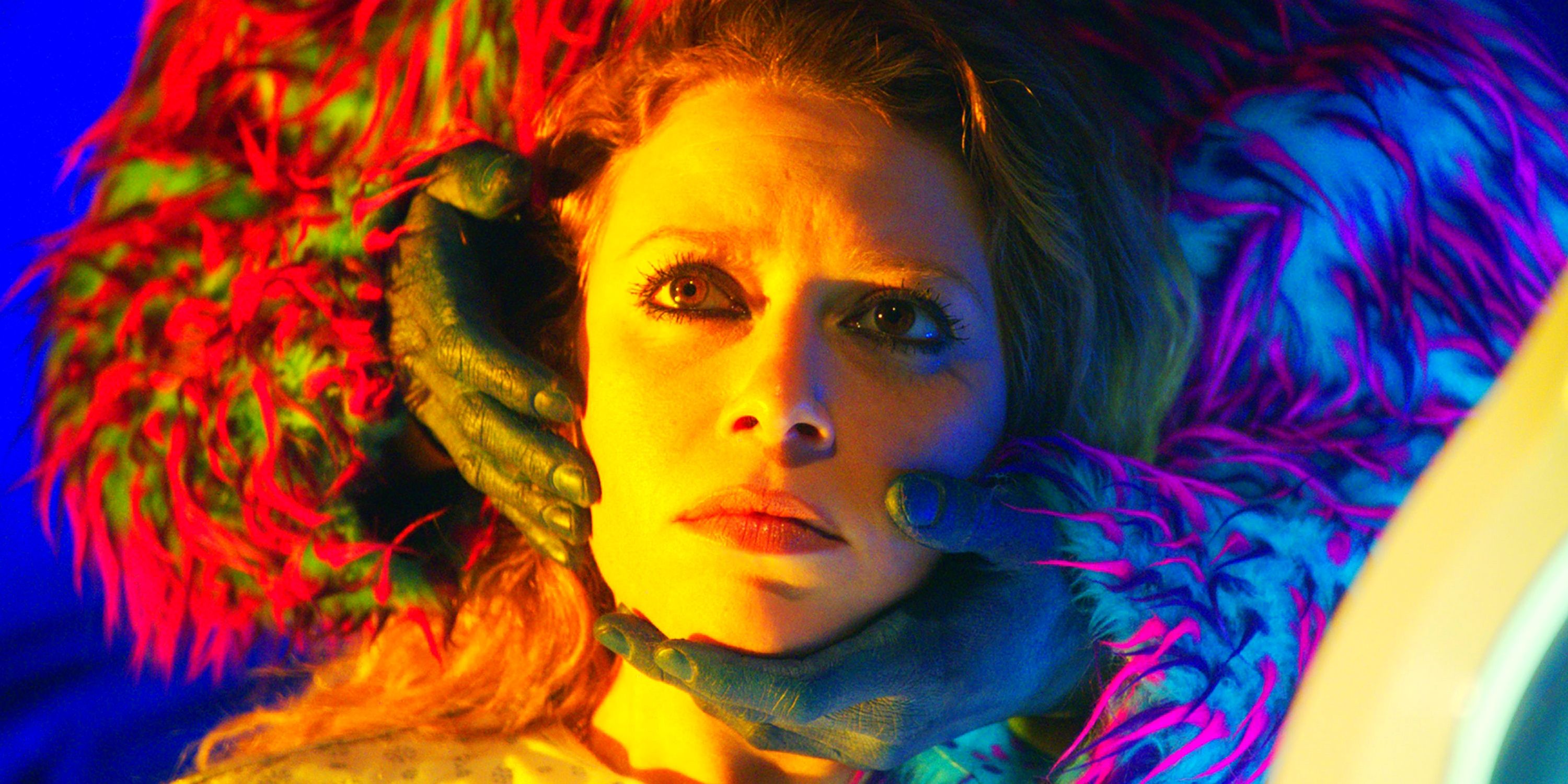 Lou, played by actor Natasha Lyonne, looks dazed as dark hands with vibrant furry arms grip her face in Antibirth.