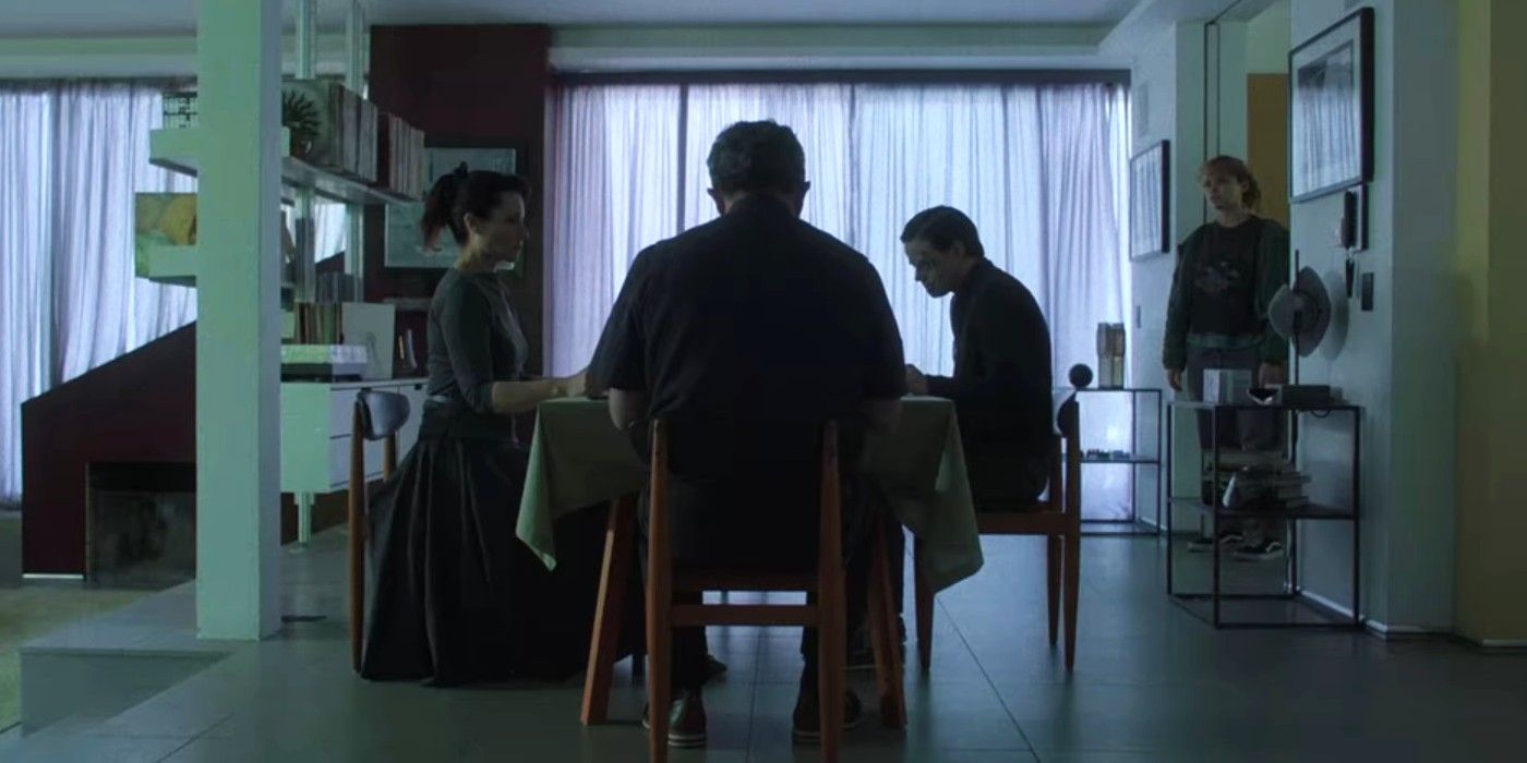 Iola Evans entering a dining room where a family of three are sitting around the table in Choose or Die.