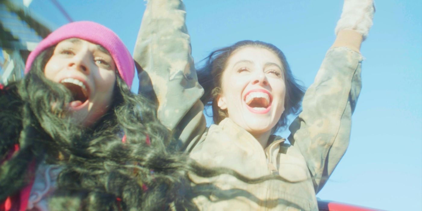 two women throw their hands in the air while on a rollercoaster