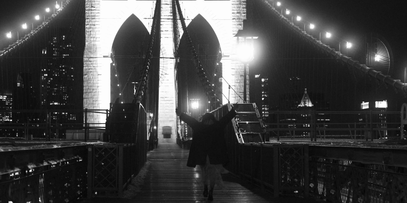 brooklyn bridge is black and white with a woman tossing her arms in the air as she walks across