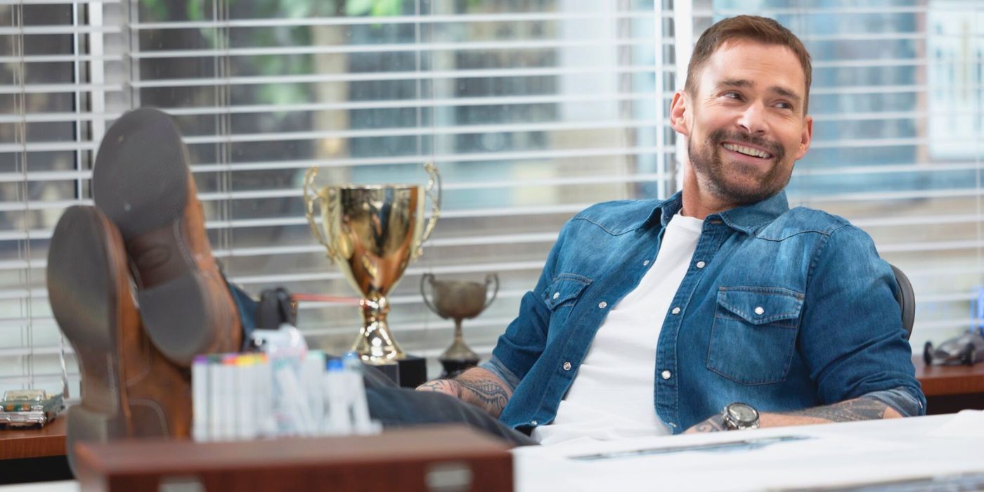 Seann William Scott as Gabe sitting in a chair with his feet up on his desk in Shifting Gears