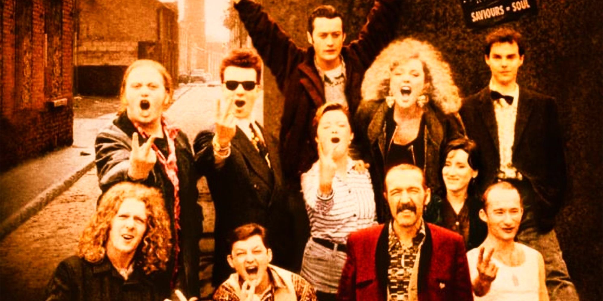 The ensemble cast of The Commitments, standing in a street cheering and giving the camera the finger.