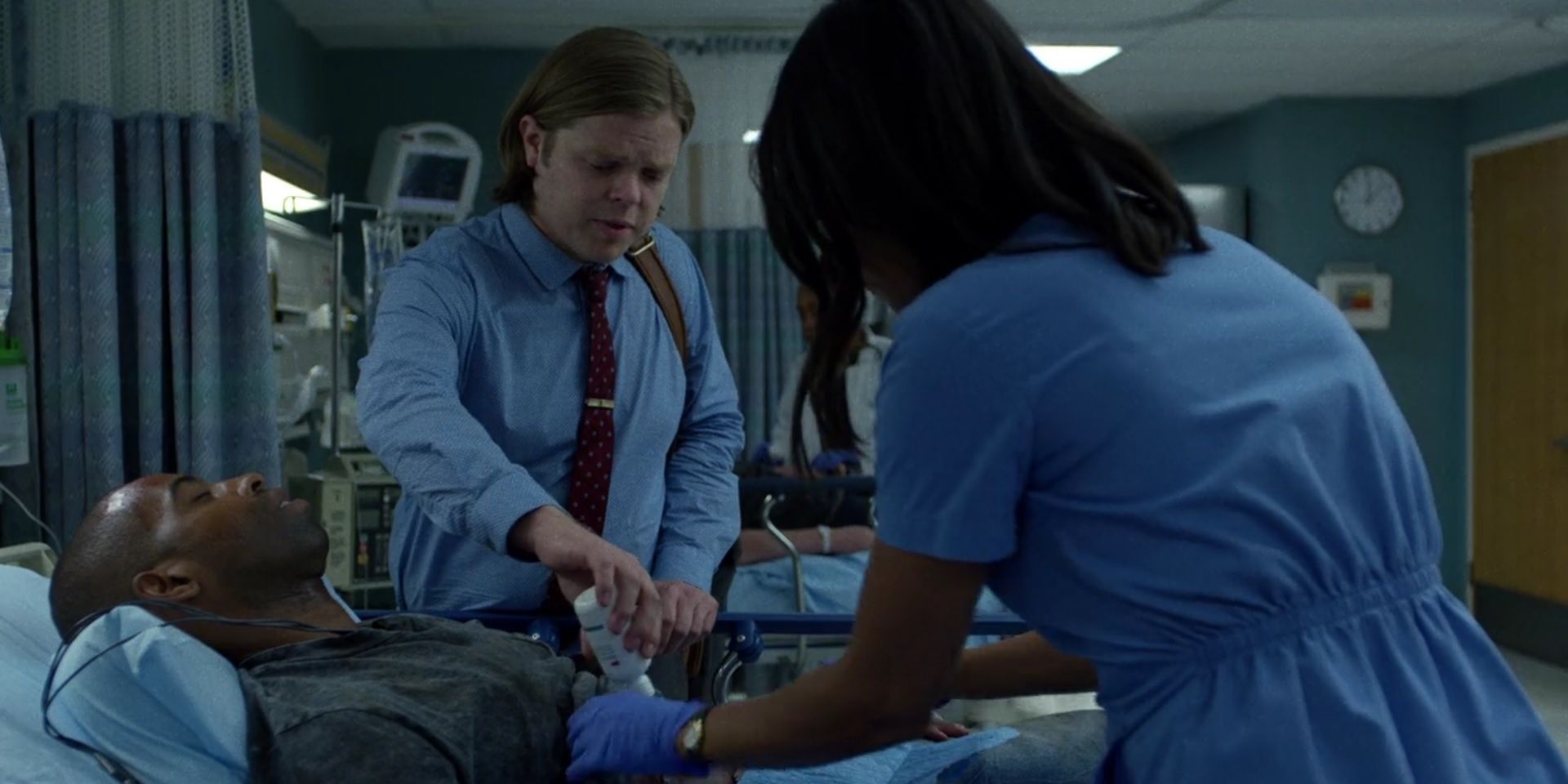 Two people tend to a person lying on a hospital bed