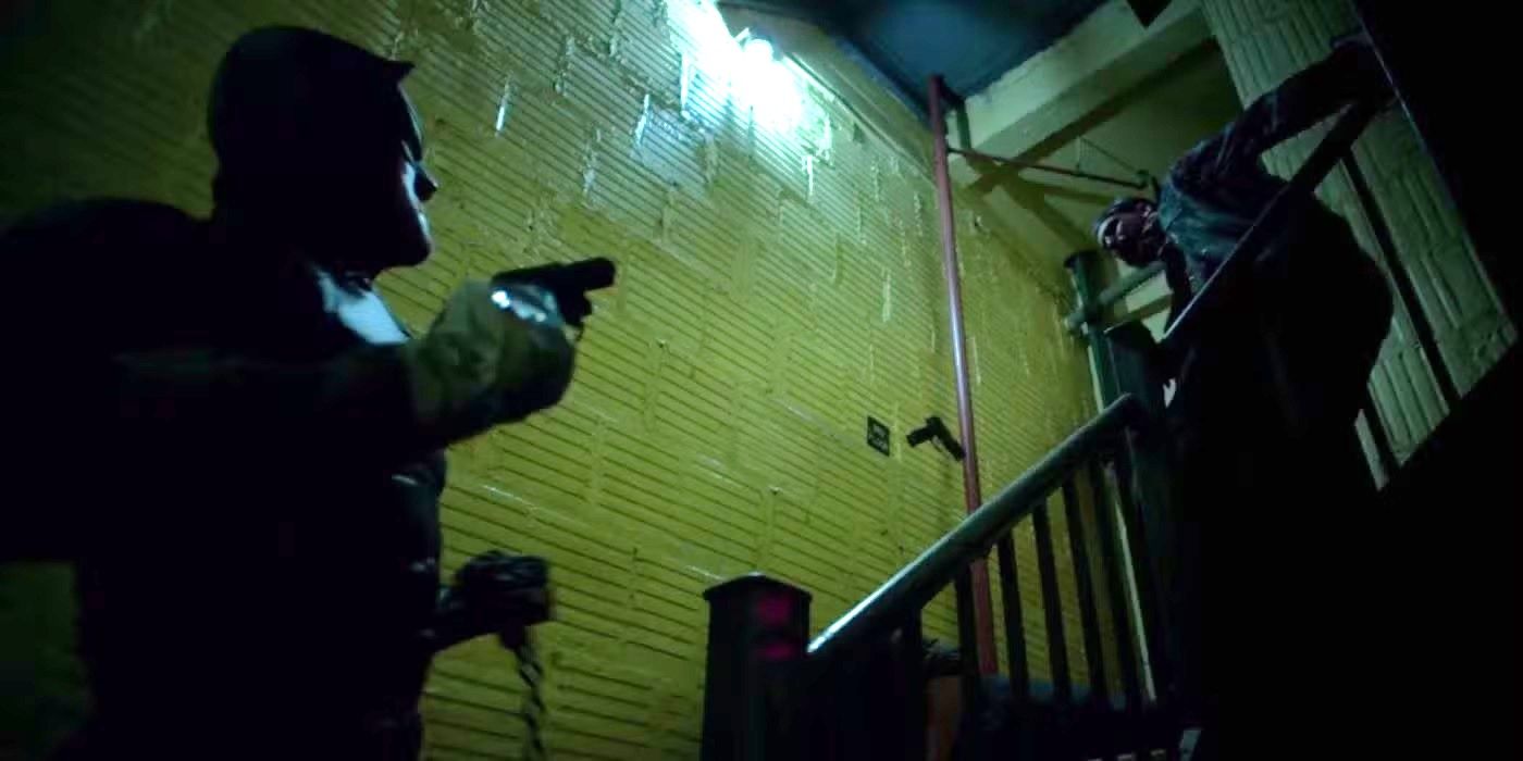 Daredevil pointing a gun at someone in a stairwell in Daredevil.