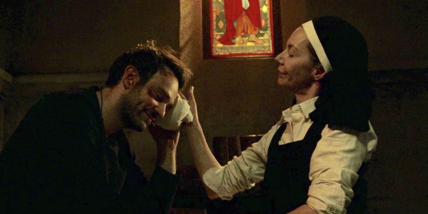 Sister Maggie comforts a wounded Matt in a church as they both smile slightly in the Daredevil TV series.