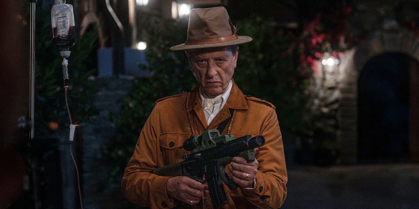 Richard E. Grant holding up a rifle and scowling in Death of a Unicorn