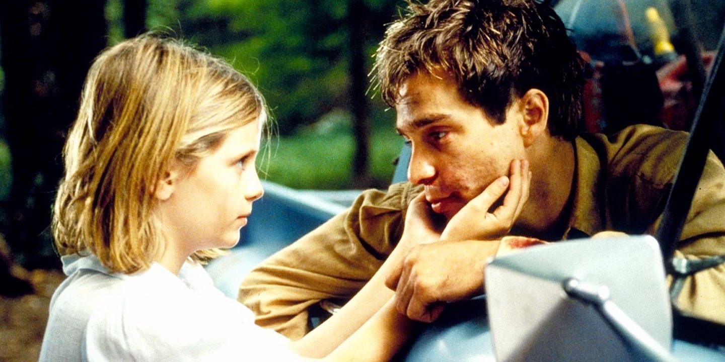 Mischa Barton as Devon touches Sam Rockwell as Trent's face as he leans out of a car window in 'Lawn Dogs'.