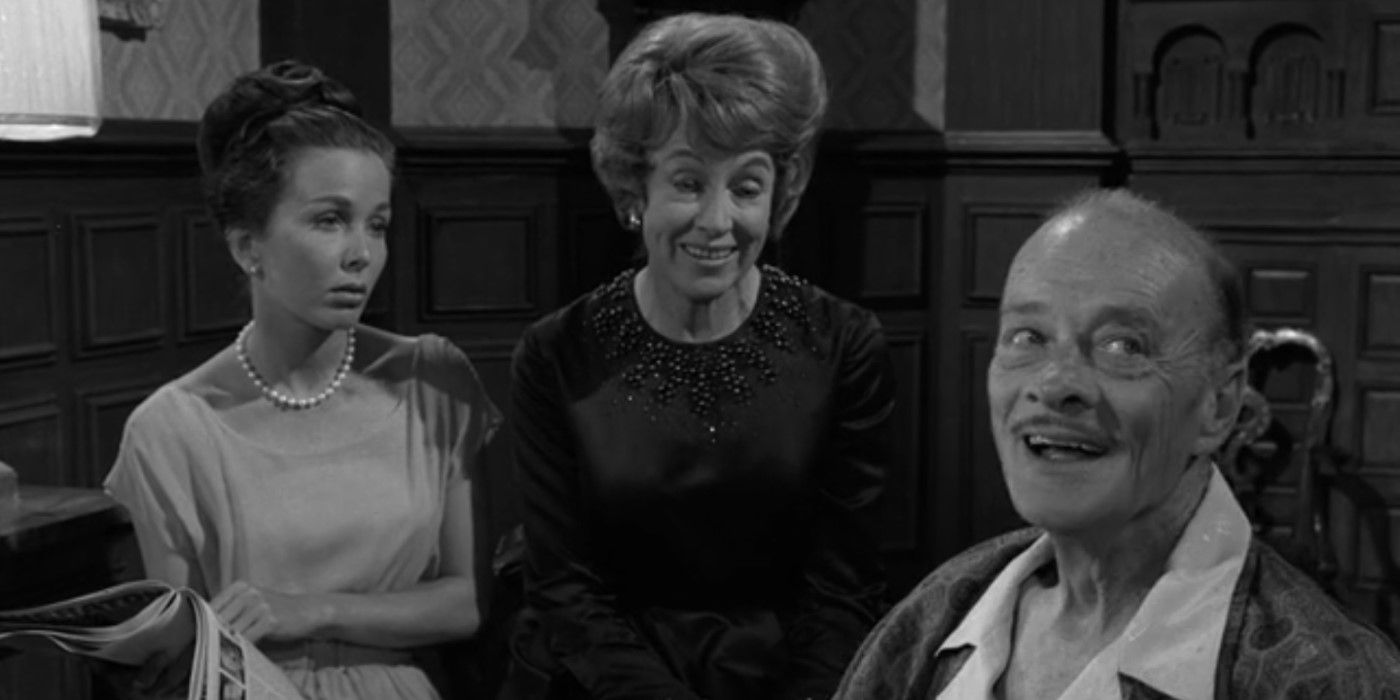 Emily (Virginia Gregg) and Paula (Brooke Hayward) standing to the side of a seated Jason Foster (Robert Keith) in The Twilight Zone&rsquo;s &ldquo;The Masks.&quot;