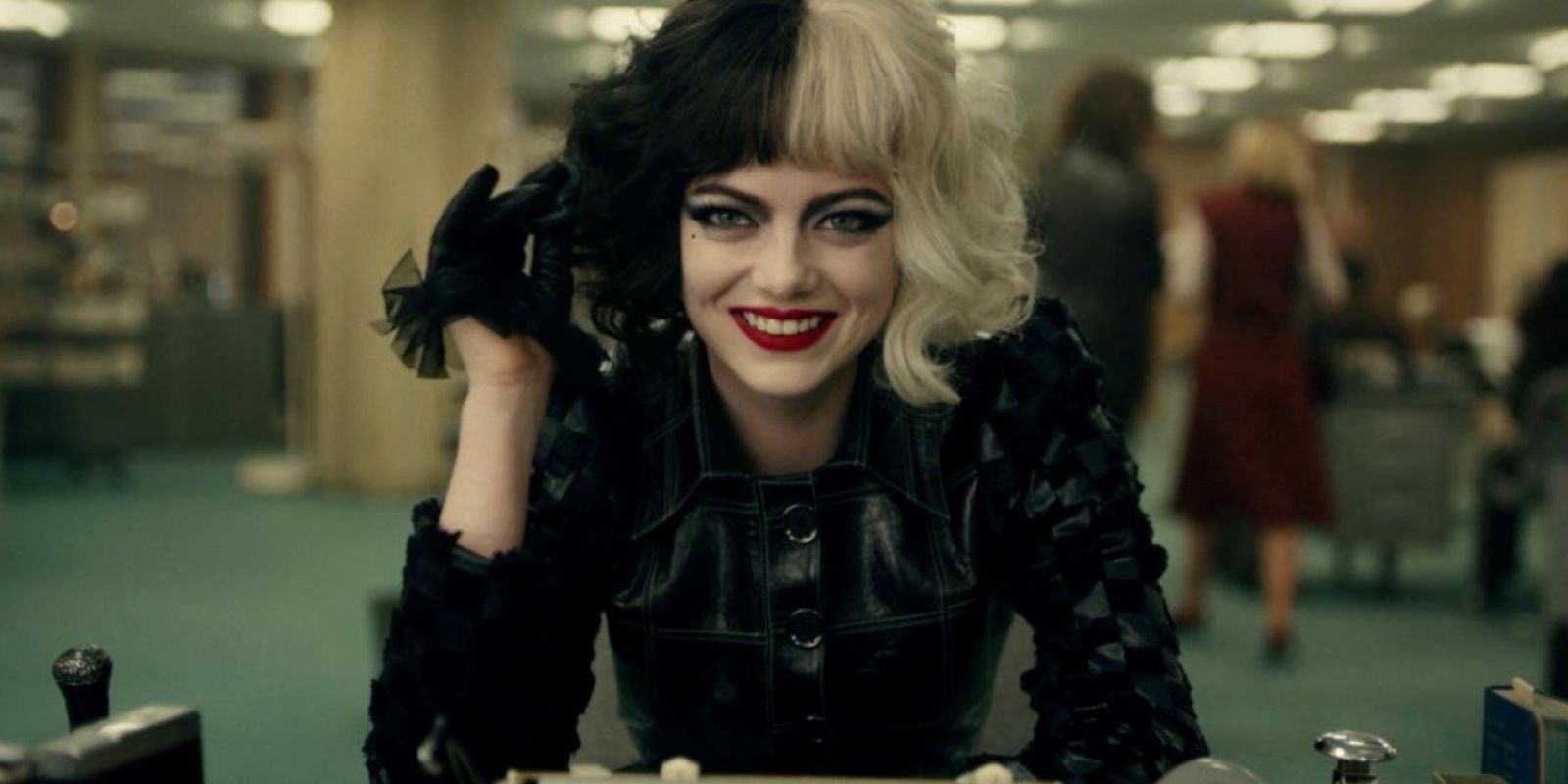 Emma Stone as Cruella smiling widely in Cruella