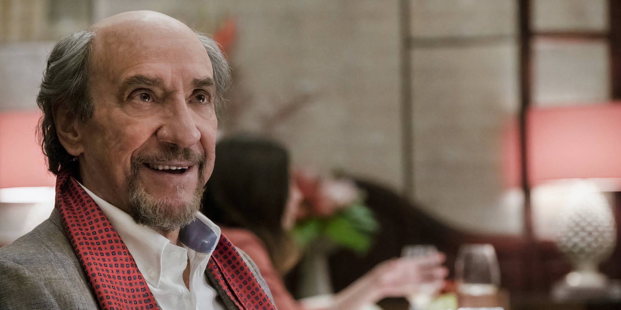 F. Murray Abraham as Bert Di Grasso smiling at someone off-camera in The White Lotus.
