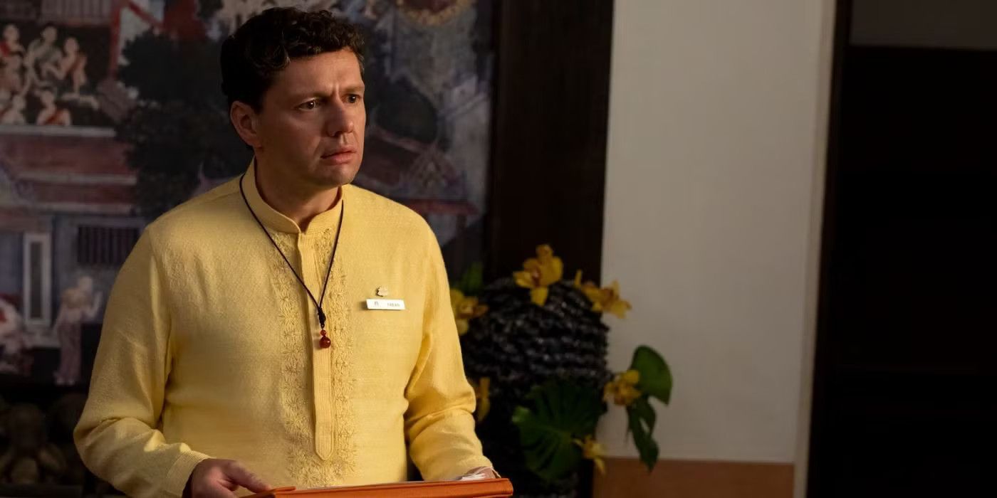 Christian Friedel as Fabian holding a tray and looking concerned in The White Lotus Season 3.