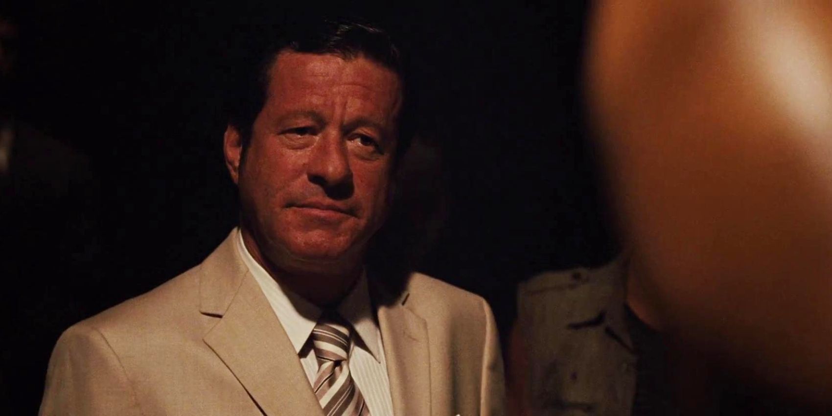 Joaquim de Almeida as Hernan Reyes in a business suit and tie talking to others in a dark setting in Fast Five.