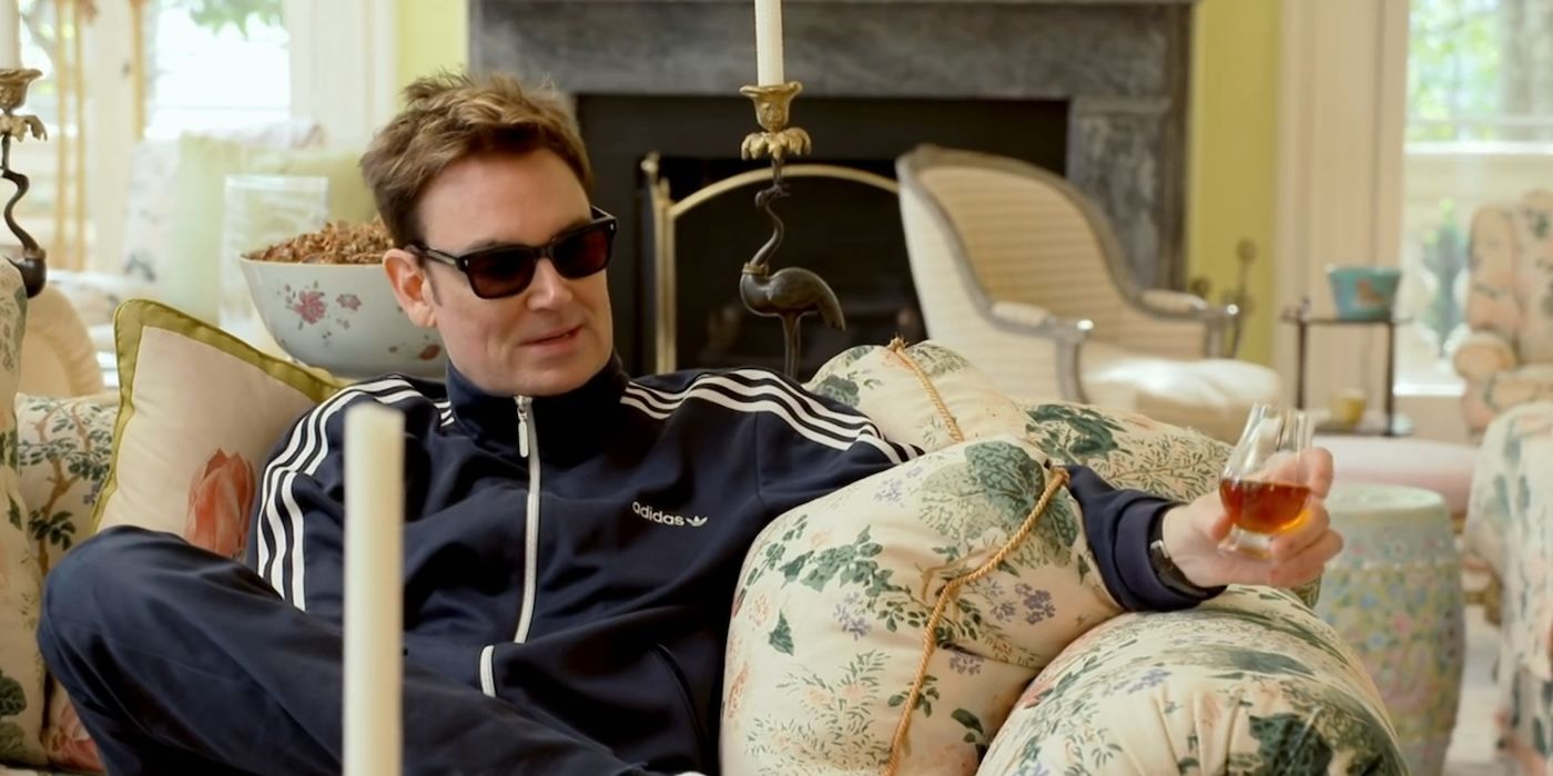 Whitney Sudler-Smith in a track suit with a drink in hand on his mother's couch on 'Southern Charm'.