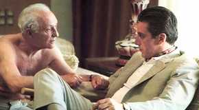 Lee Strasberg as Hyman Roth leaning in to talk to Al Pacino as Michael Corleone in The Godfather Part II