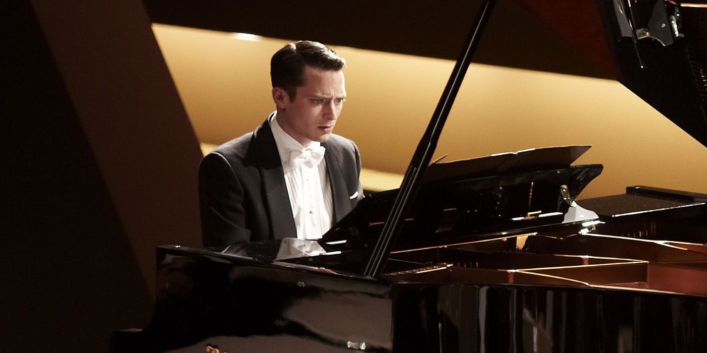 Elijah Wood dressed in a tux and looking concerned while sitting at a piano onstage in Grand Piano.