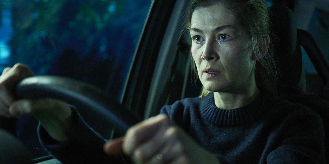 Rosamund Pike gripping a steering wheel looking ahead with intensity 