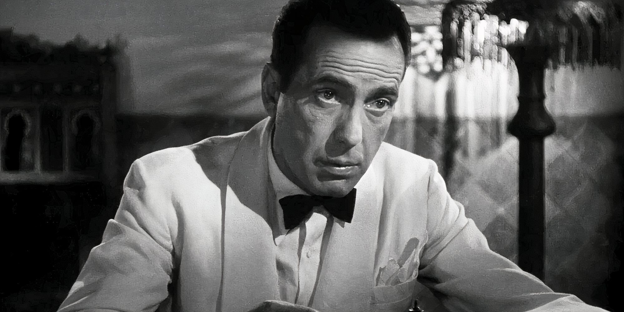 Humphrey Bogart as Rick Blaine in a white tuxedo looking intently off-camera in Casablanca, 1942.